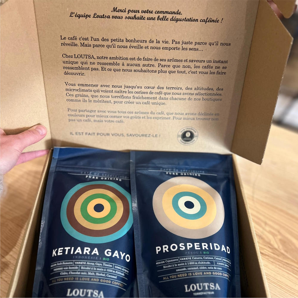 Une boîte renfermant deux sachets de café, offrant une sélection pour les passionnés de cette boisson.