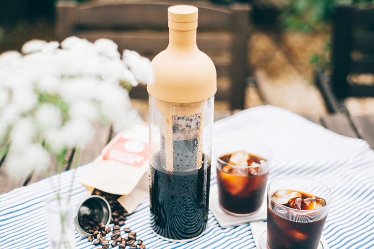 bouteille à infuser pour le café HARIO, sur une table, avec un sachet de café et deux verres de cold brew