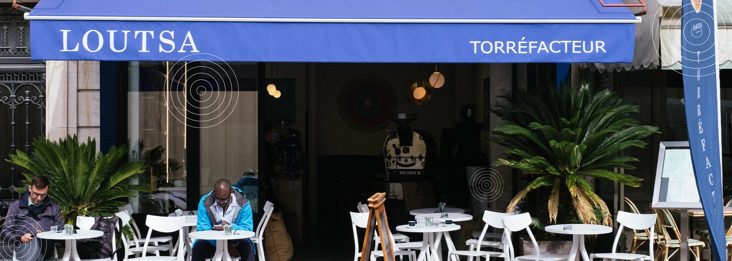 Devanture de la boutique de torréfaction Loutsa, avec terrasse et client assis en extérieur à une table blanche, sous un auvent bleu.
