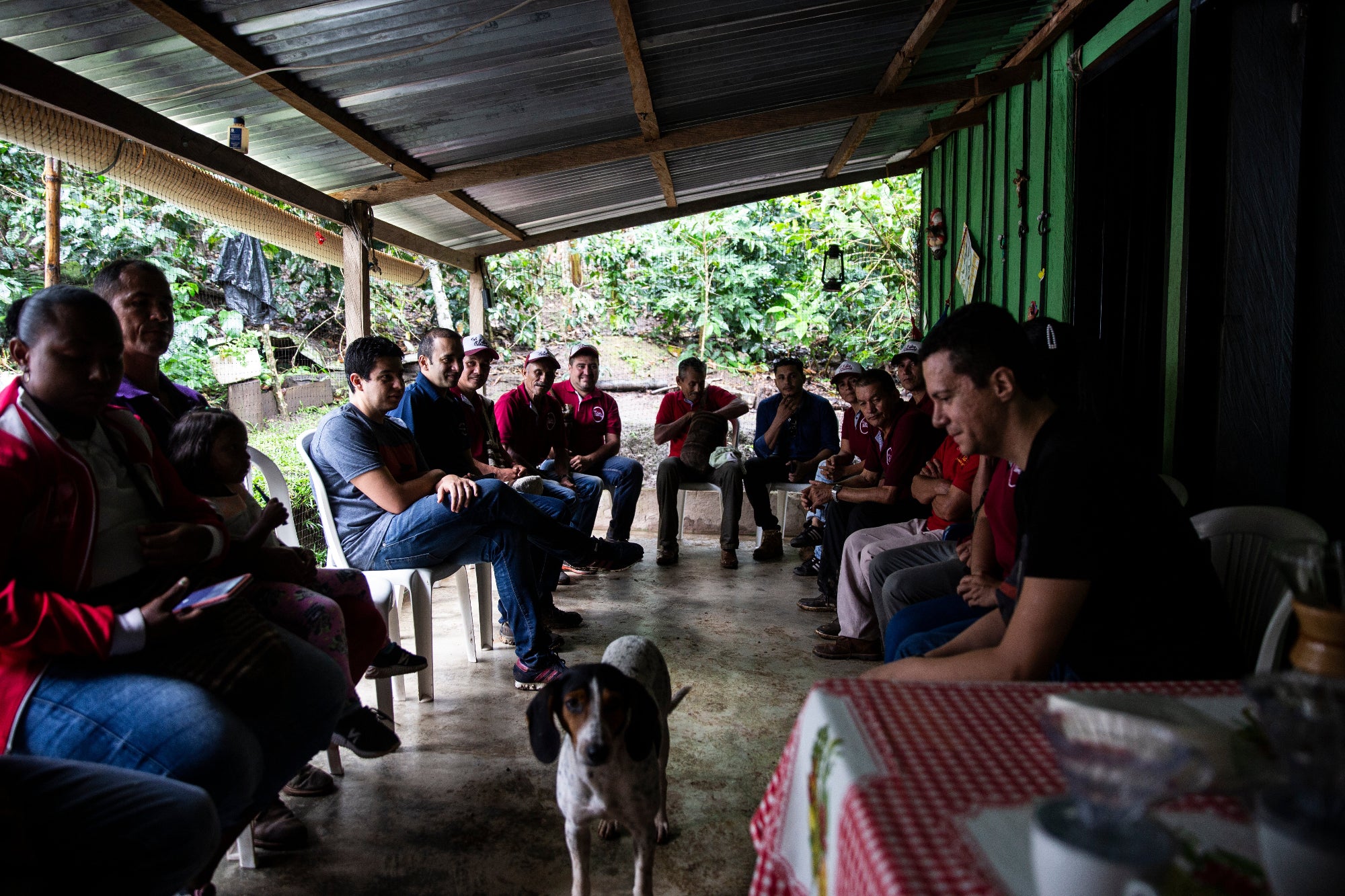 personnes de la ferme de Agustin Codazzi, assises en cercles sous un tonnelle avec un chien au centre